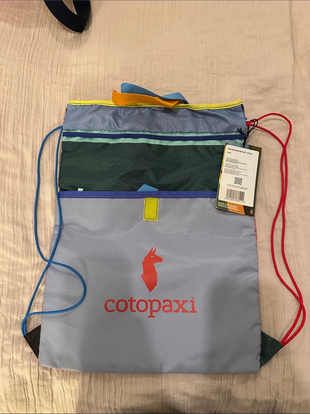 cotopaxi Light Blue Drawstring Pack with Red Logo and Multicolor Accents